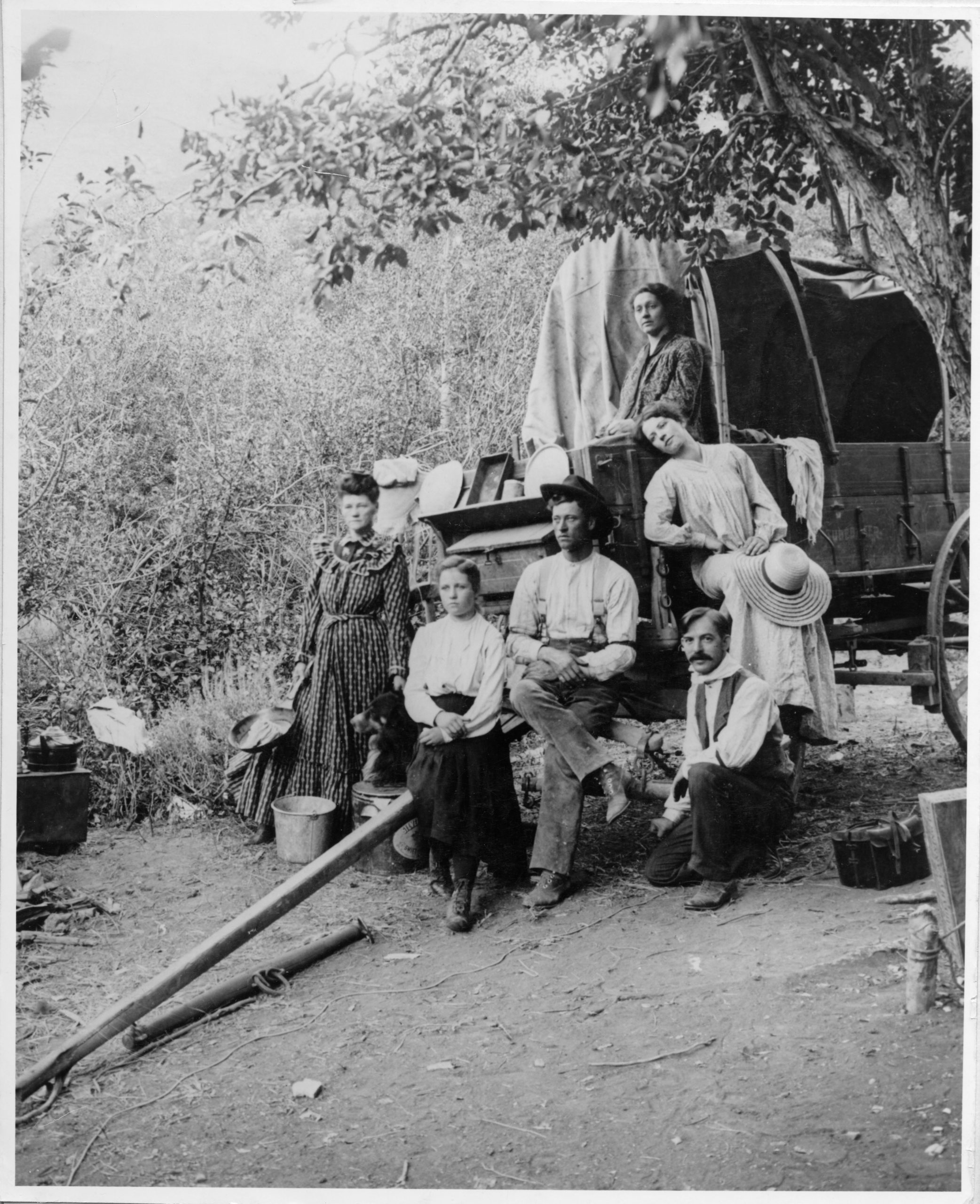 A photographer (right) and others in a staged scene on a covered wagon depicting life on the trail.
